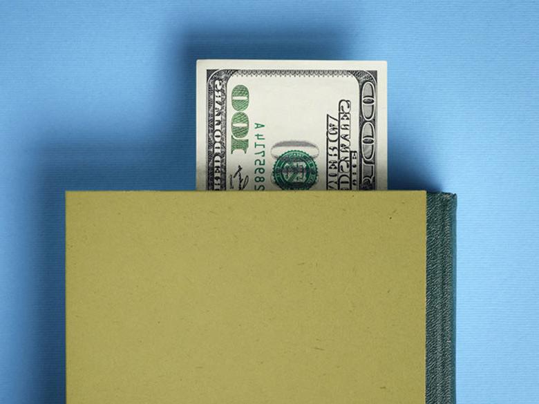 100 dollar bill used as book mark in a green book