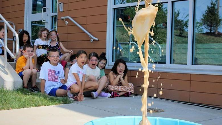 Campers from last summer's science camp watch a bottle volcano erupting